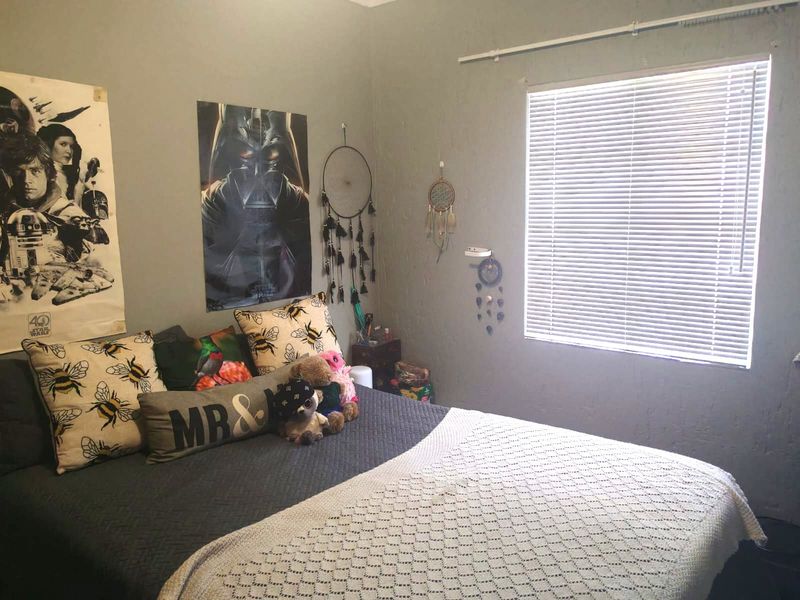 A bedroom featuring neutral wall paint and a window fitted with venetian blinds.