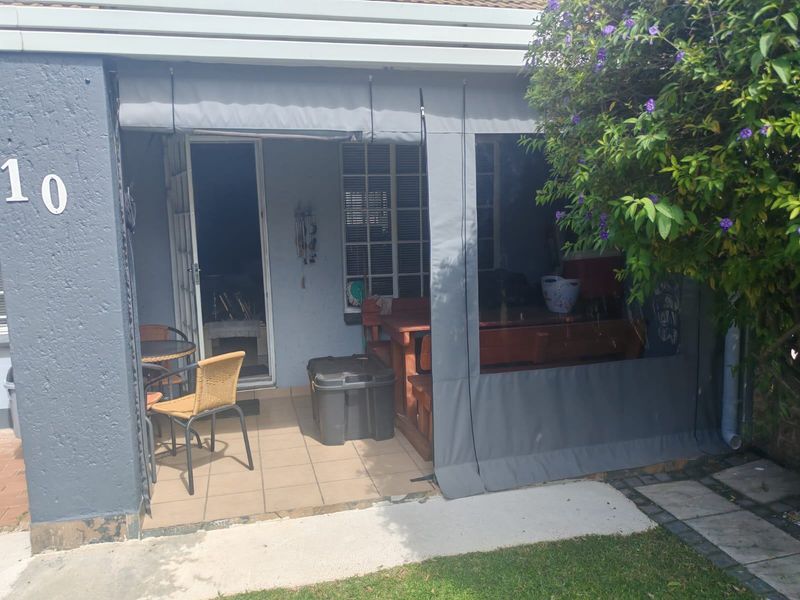 A covered patio area featuring tiled flooring, retractable canvas blinds for weather protection, and direct access to the interior through a sliding door.