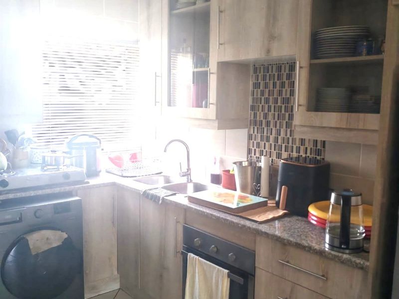 Compact kitchen featuring wood-look cabinetry, granite countertops, mosaic tile backsplash, and integrated oven, providing a functional workspace with ample storage.
