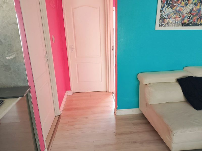 A living area featuring laminate flooring and interior panel doors, currently finished with vibrant wall paint.