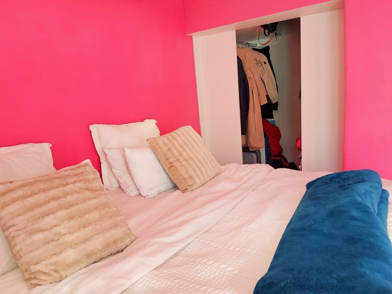 A bedroom featuring bright pink walls and a built-in closet with sliding doors.