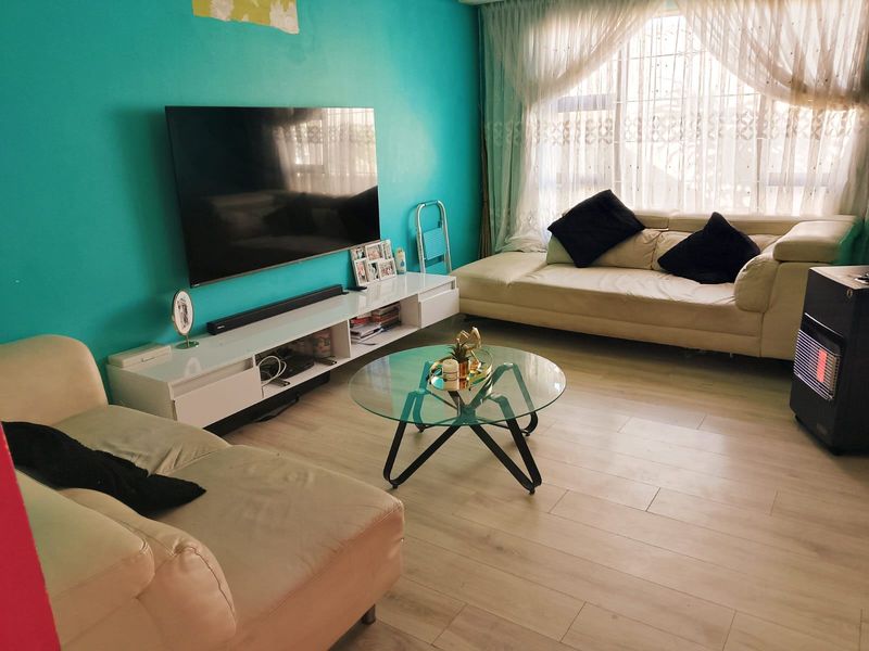 A comfortable living room featuring light-toned laminate flooring and a bright accent wall, providing a functional space for relaxation and entertainment.