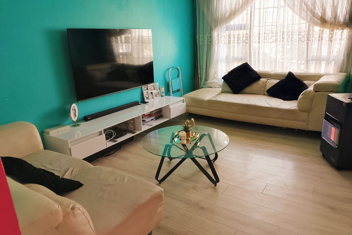 A comfortable living room featuring light-toned laminate flooring and a bright accent wall, providing a functional space for relaxation and entertainment.