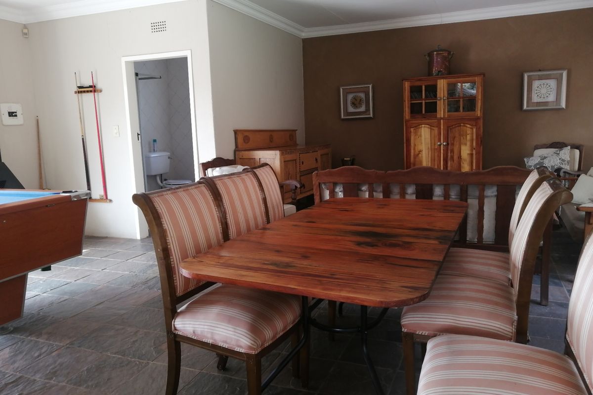 A spacious living area featuring slate tile flooring, crown molding, and recessed lighting, with an adjacent bathroom visible through the doorway.