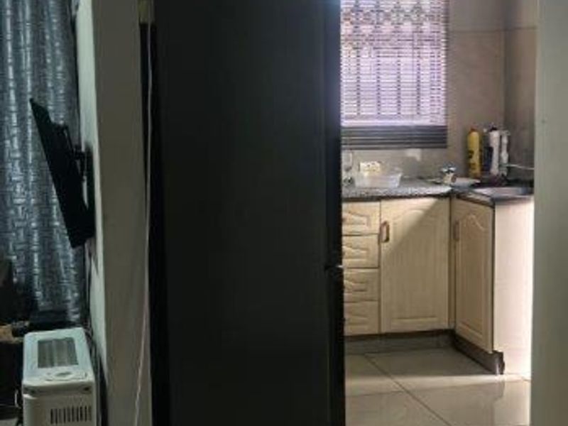 A functional kitchen area featuring tiled flooring and built-in cabinetry, viewed from an adjacent living space.