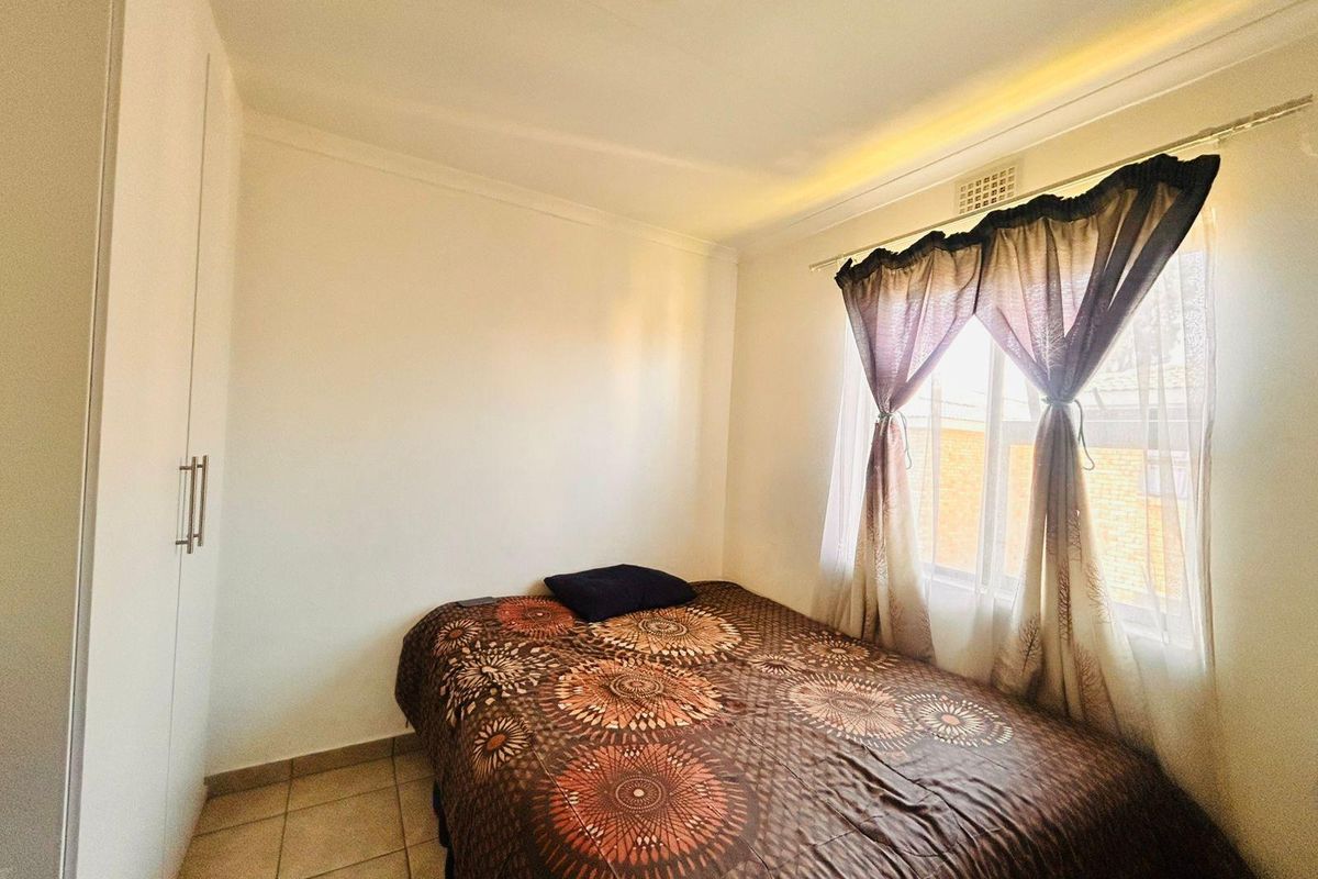 A compact bedroom featuring tiled flooring and a built-in wardrobe, providing functional storage space.
