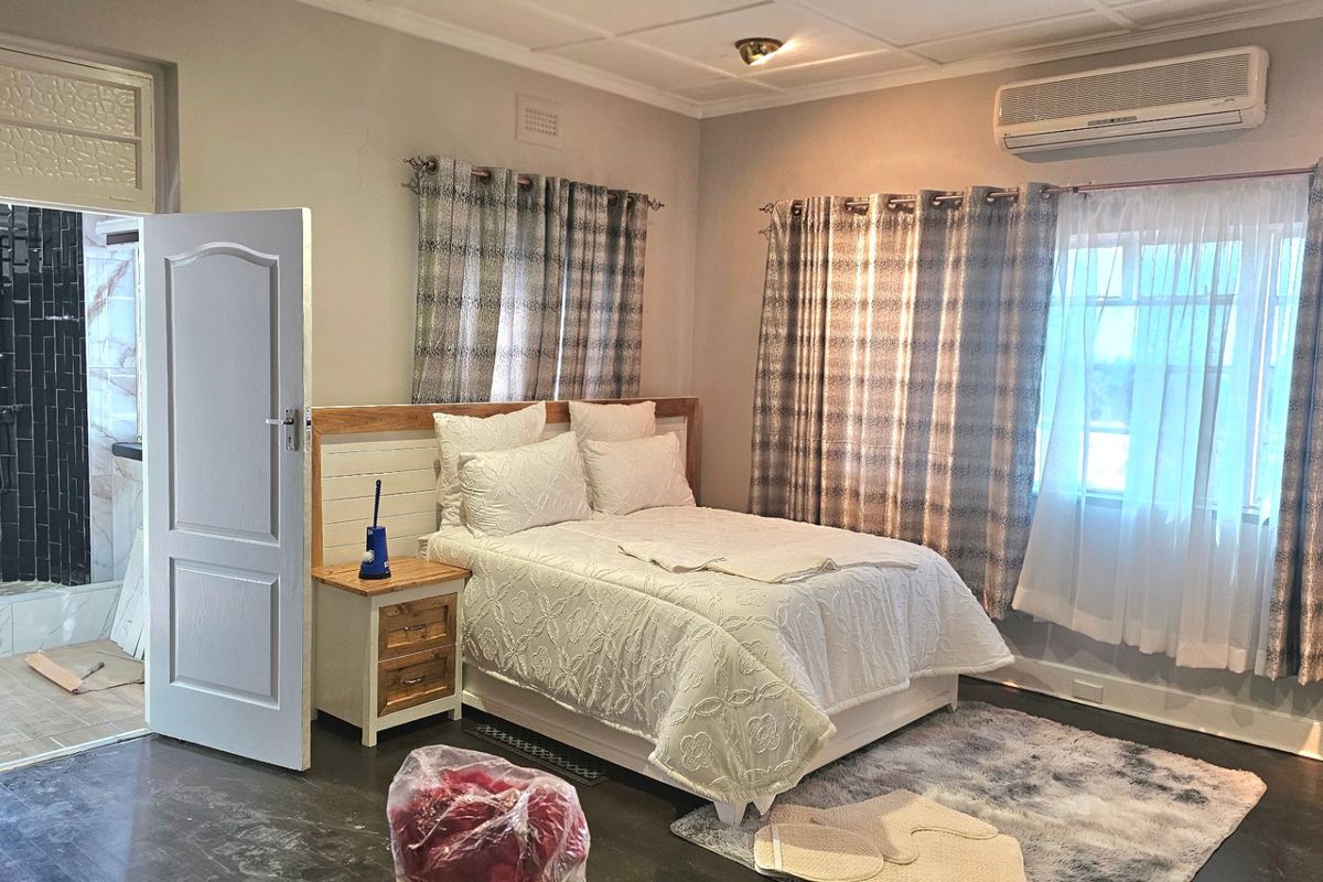 Spacious bedroom featuring an en-suite bathroom, air conditioning unit, and neutral finishes, offering a comfortable and functional living space.