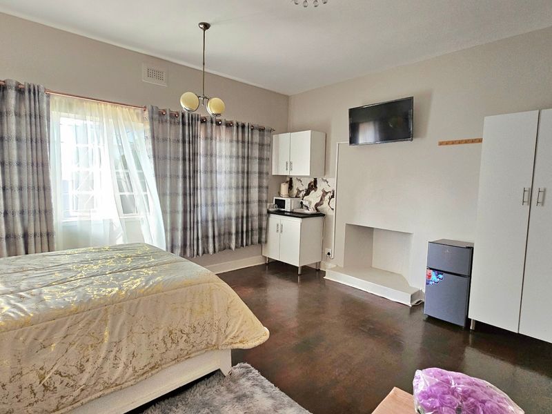 Spacious bedroom featuring dark hardwood flooring, a built-in fireplace, and integrated cabinetry, offering a functional layout with natural light.