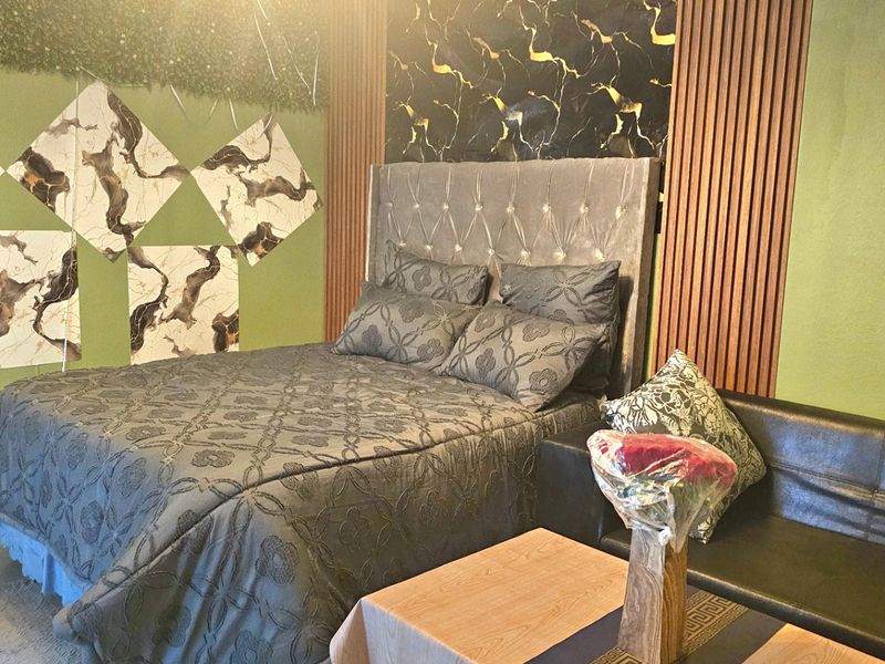 A bedroom featuring decorative slatted timber wall paneling, marble-effect wall accents, and an upholstered headboard.