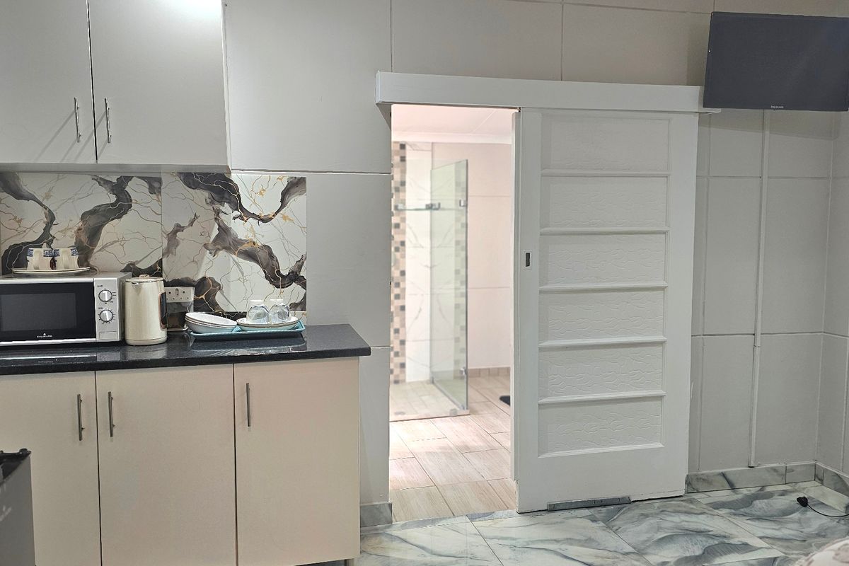 Compact kitchen area featuring built-in cabinetry, stone countertops, and a decorative backsplash, with a sliding door providing access to an adjacent bathroom.