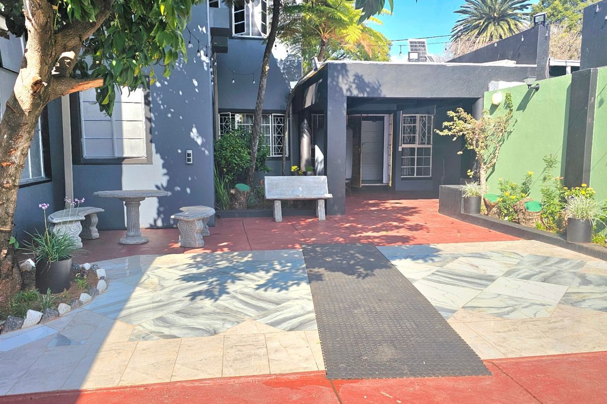 A rear courtyard area featuring a paved patio, security bars on windows, and boundary walls, providing a functional outdoor space for relaxation.