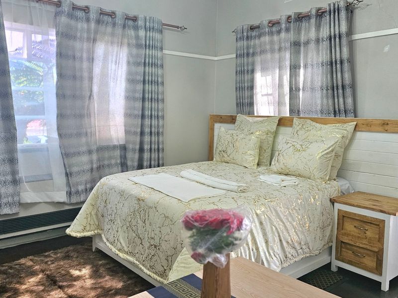 A bedroom featuring a window-mounted air conditioning unit, classic picture rails, and skirting boards, with neutral wall tones.