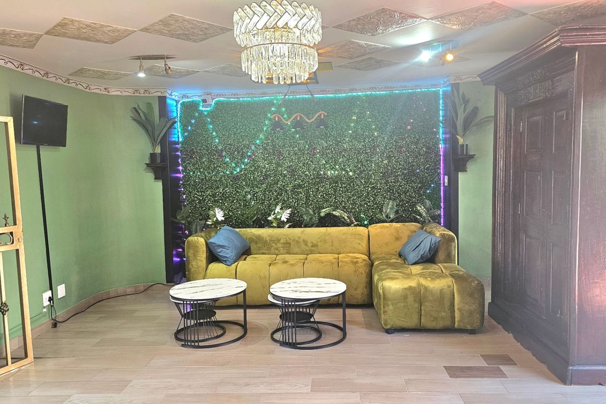 A living room featuring tiled flooring, decorative ceiling panels, and a central crystal chandelier.