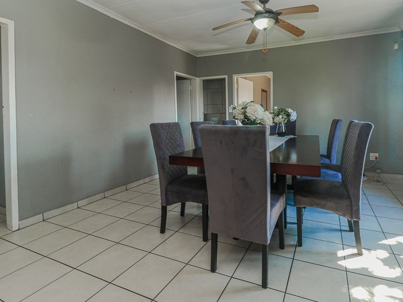 A functional dining room featuring tiled flooring, a ceiling fan, and neutral wall finishes, providing a practical space for family meals.