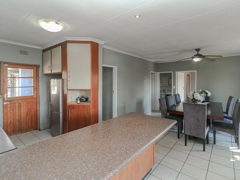 Open-plan kitchen and dining area featuring tiled flooring, timber cabinetry, and a ceiling fan, offering a functional layout for daily living.