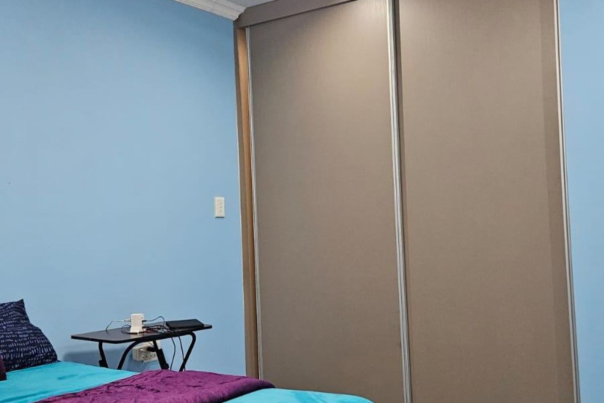 A bedroom featuring tiled flooring, crown molding, and a large built-in sliding door wardrobe.