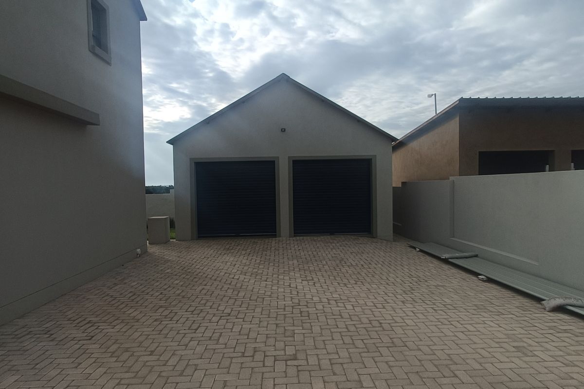 A detached double garage with a paved driveway and surrounding boundary walls.