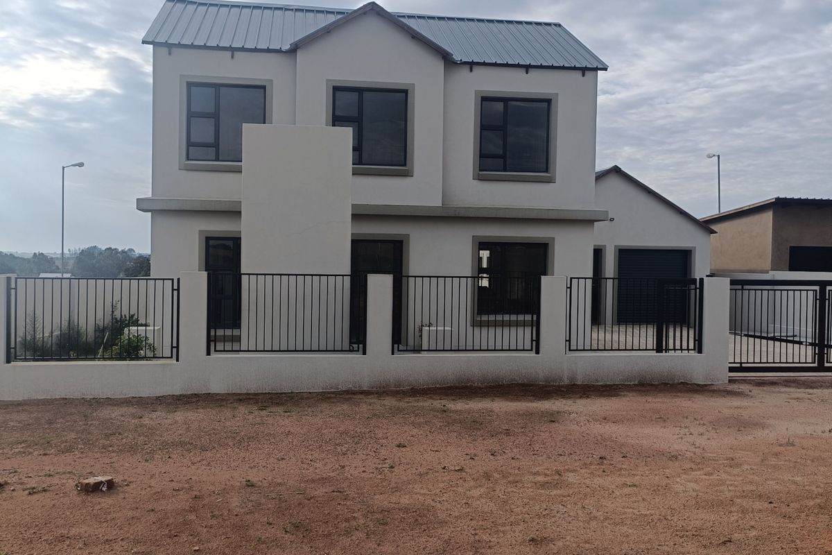 A modern double-storey residential property featuring a metal roof, aluminium window frames, and a secure perimeter fence with a gated driveway.