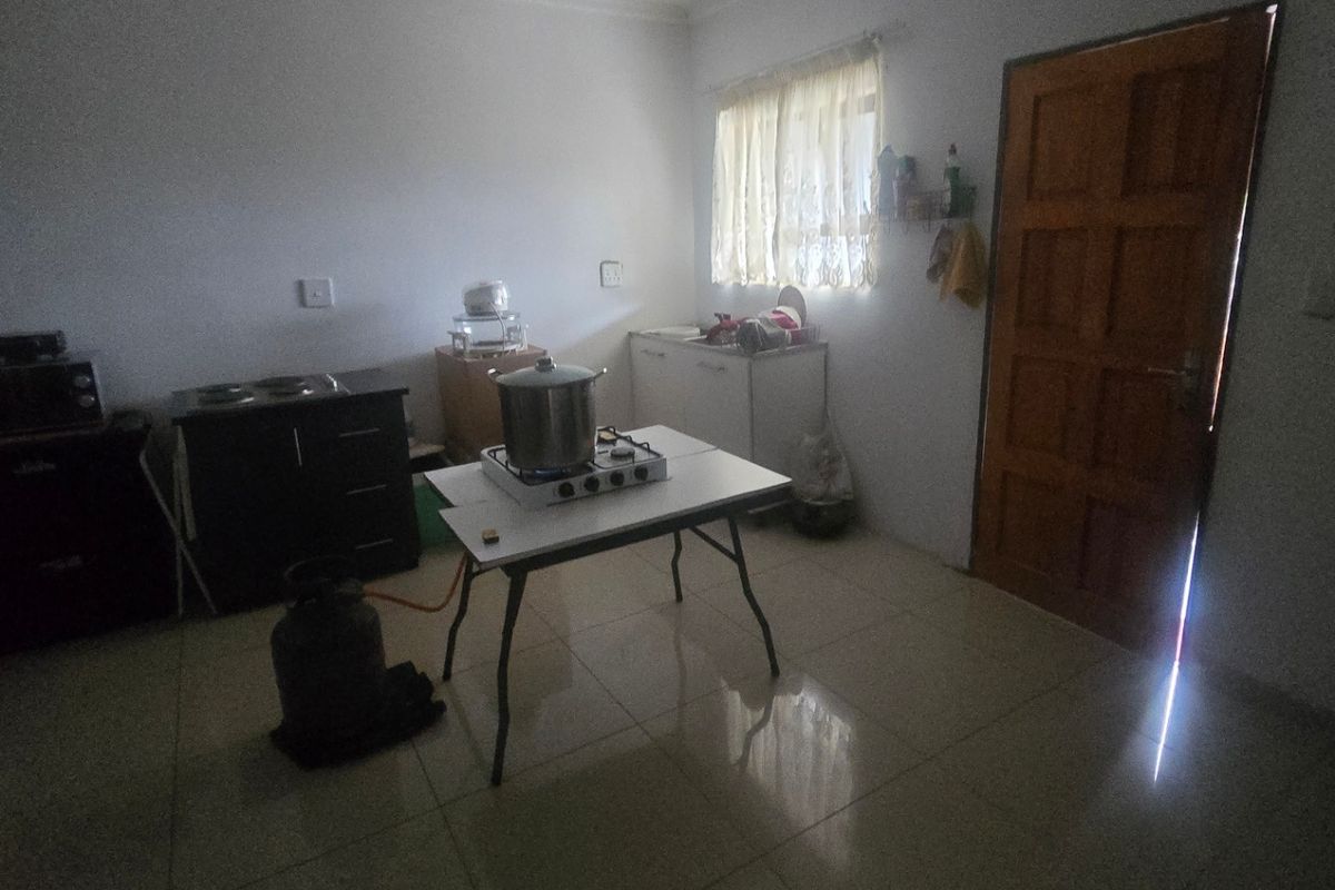 A basic kitchen area featuring tiled flooring and a wooden door, currently lacking built-in cabinetry or permanent kitchen fixtures.