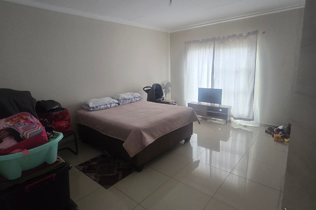 A spacious bedroom featuring neutral wall finishes and large format floor tiles, providing a clean and functional foundation for personal styling.