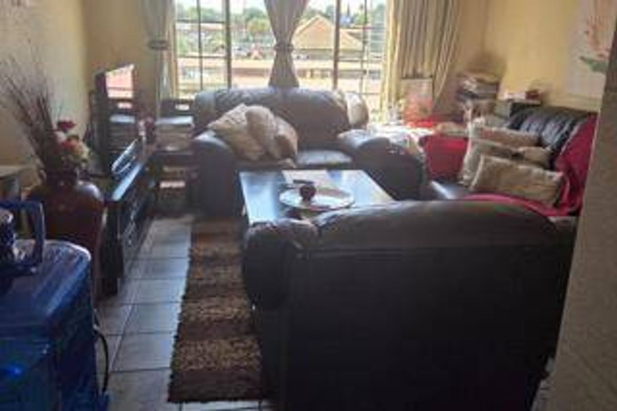 A living room featuring tiled flooring and a sliding glass door providing natural light and access to the exterior.