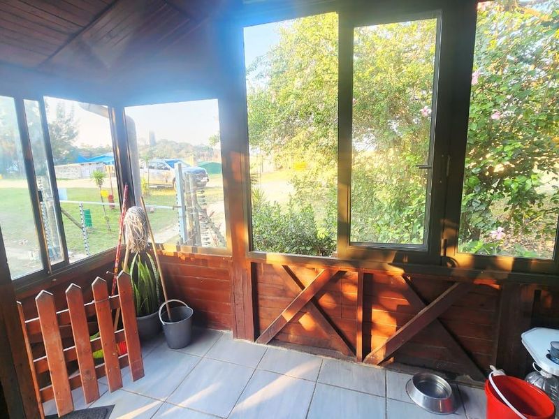 A sun-filled enclosed patio featuring timber-framed walls, large glass windows, and tiled flooring, offering a bright and versatile space for relaxation.