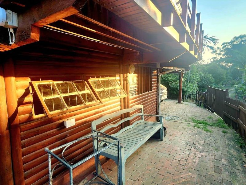A rustic timber-clad townhouse exterior featuring a brick-paved patio area and an overhead timber balcony structure.