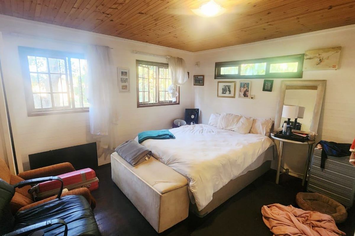A bedroom featuring a timber-clad ceiling, security bars on the windows, and a horizontal clerestory window providing natural light.