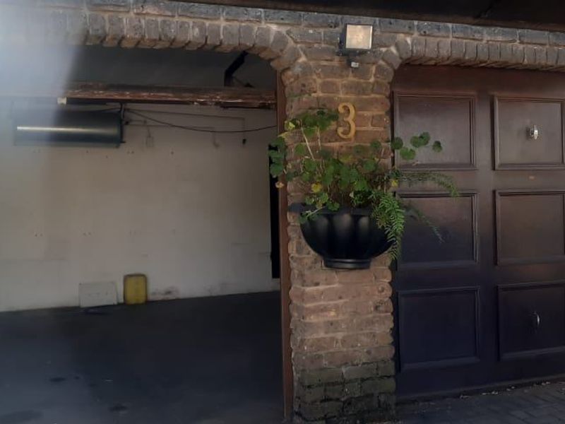 A view of a residential garage featuring a dark sectional door and exposed brickwork exterior.