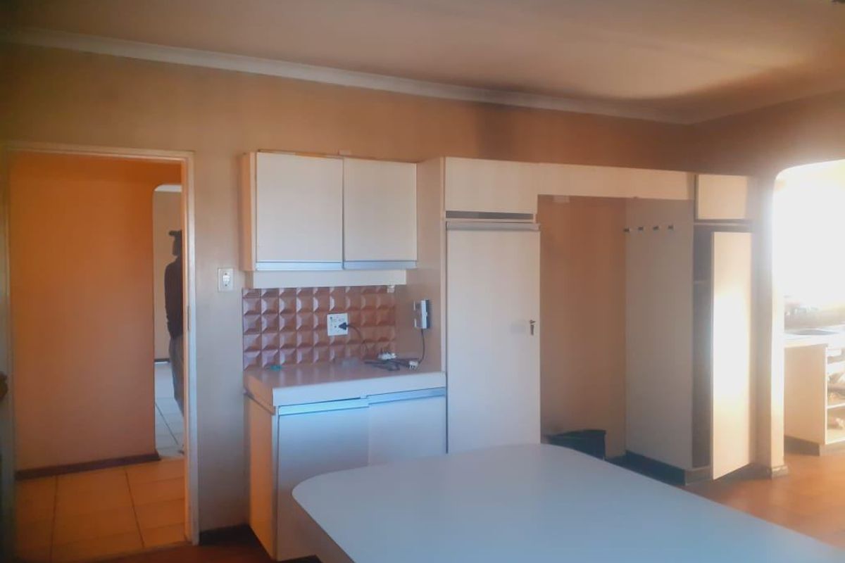 A dated kitchen featuring built-in cabinetry, a tiled backsplash, and laminate countertops, offering potential for a modern renovation.