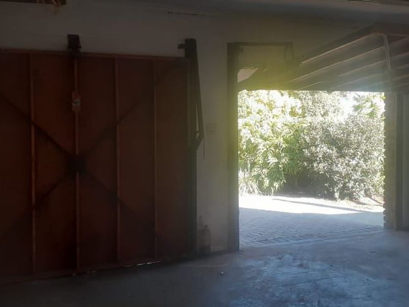 A functional garage space featuring a tilt-up door, concrete flooring, and an accessible electrical distribution board, offering secure vehicle storage or utility potential.