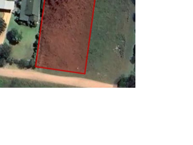 An aerial view of a vacant residential plot with red boundary lines indicating the property perimeter.