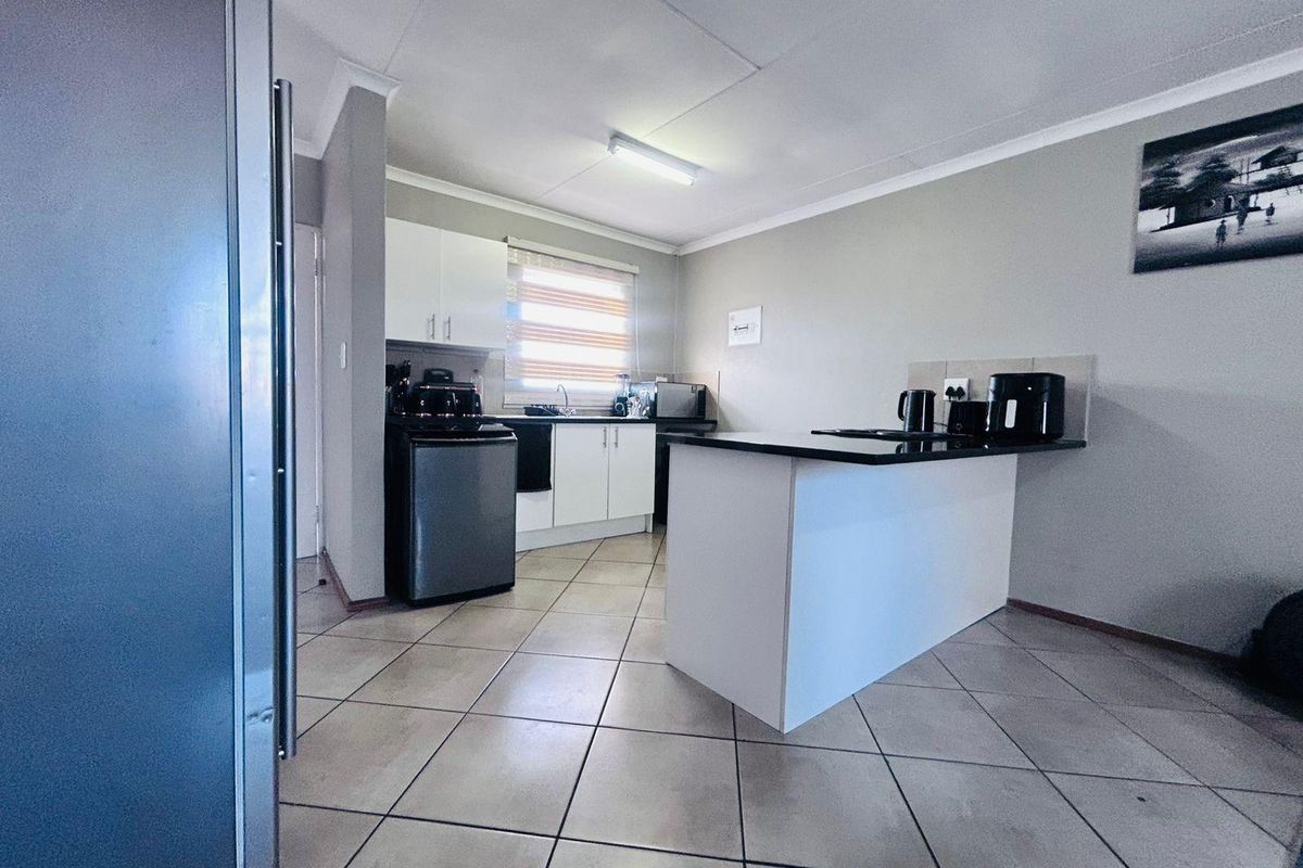 A functional kitchen featuring white cabinetry, a central island with a dark countertop, and tiled flooring, providing a clean and practical workspace.
