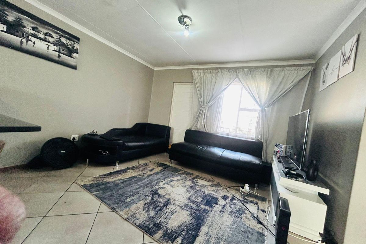 A functional living room featuring tiled flooring and a coved ceiling, providing a neutral base for comfortable daily living.