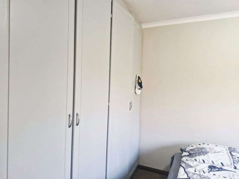 A bedroom featuring neutral walls and floor-to-ceiling built-in cupboards providing ample storage space.