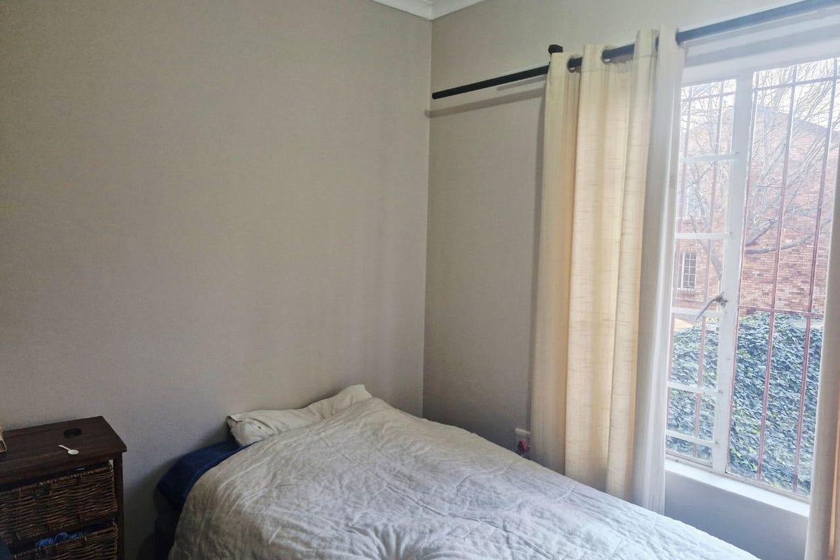 A simple bedroom featuring a window with security bars and neutral wall finishes.