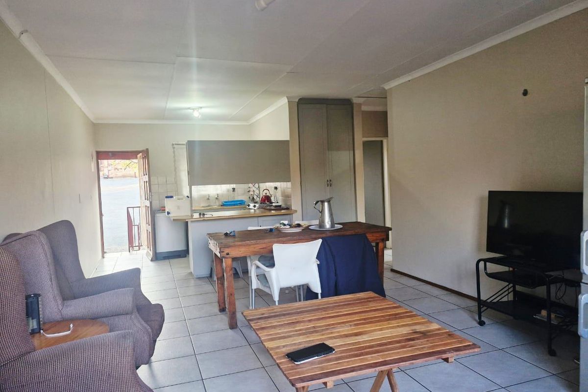 Open-plan living and kitchen area featuring tiled flooring, built-in cabinetry, and a functional layout with direct access to the exterior.
