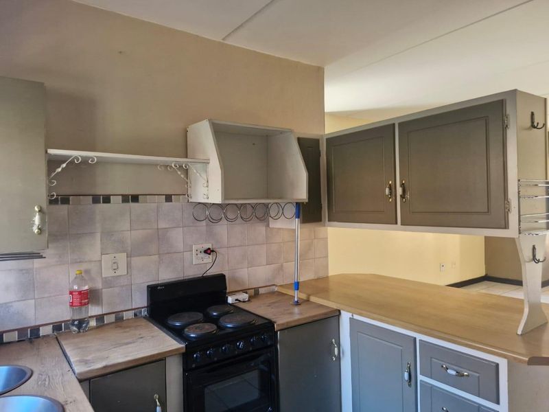 A functional kitchen featuring built-in cabinetry, laminate countertops, a tiled backsplash, and an integrated electric stove and oven.