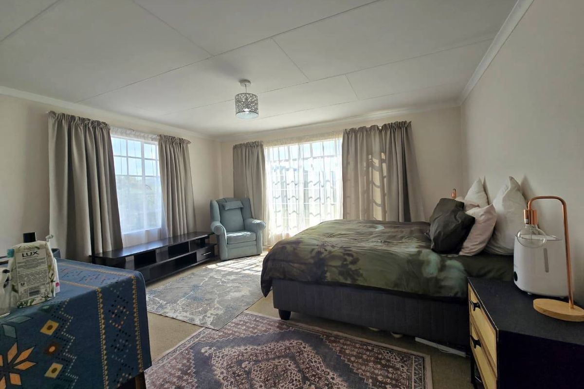 A spacious bedroom featuring large windows that provide ample natural light, finished with ceiling tiles and coving.