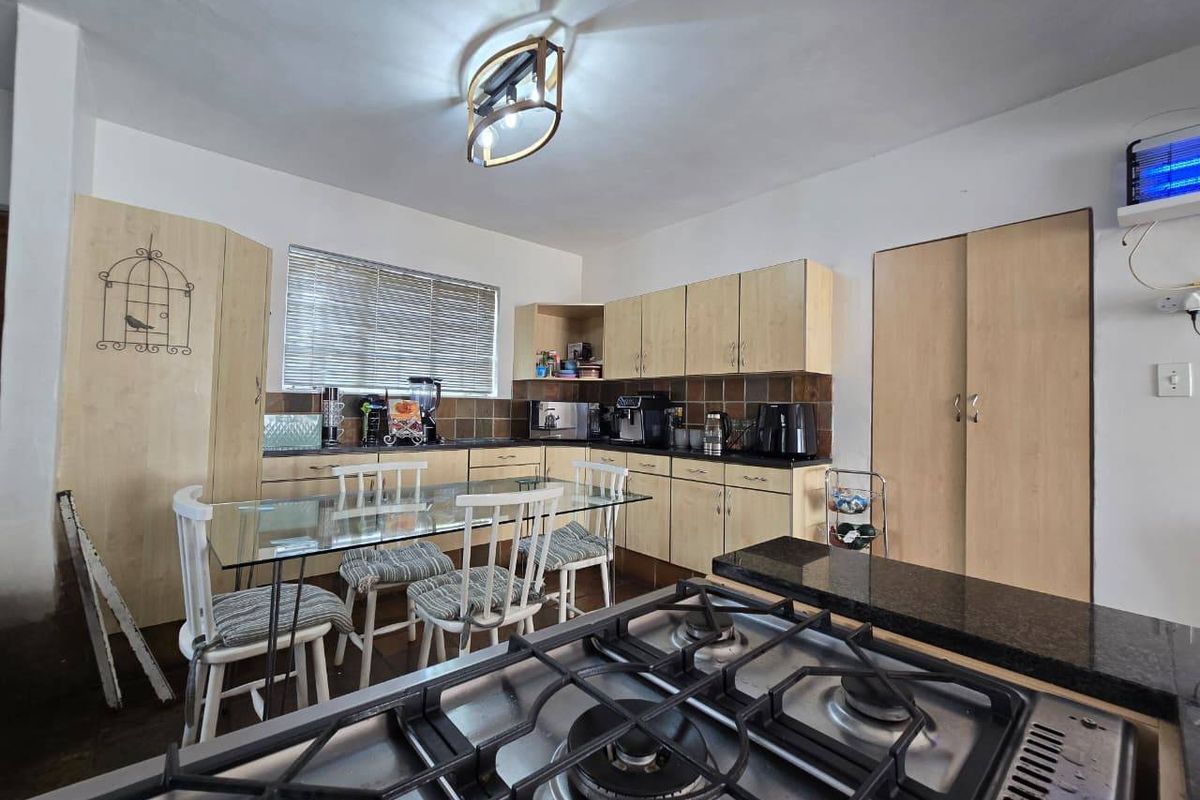 Functional kitchen featuring light wood cabinetry, granite countertops, a gas hob, and a tiled backsplash, offering a practical layout for daily cooking.