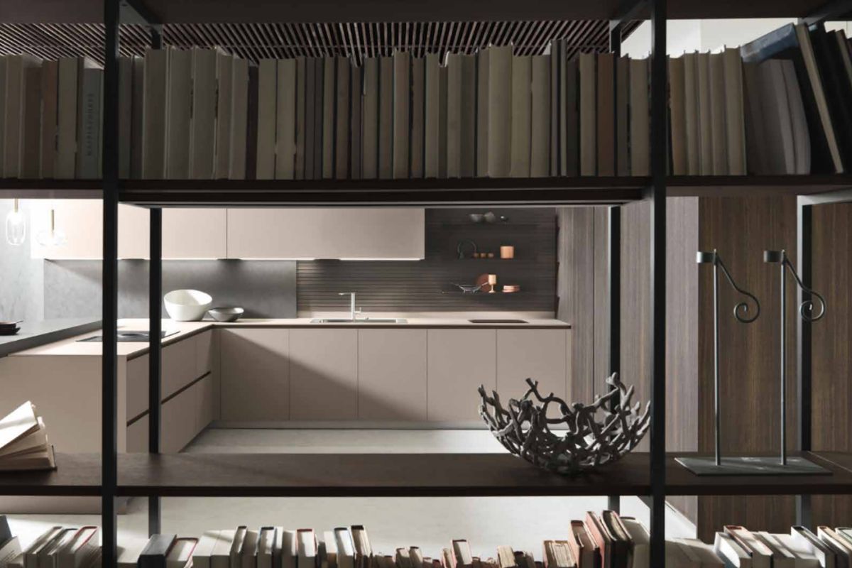 A modern, high-end kitchen featuring sleek cabinetry, integrated sink, and a sophisticated slatted ceiling design, viewed through a decorative open shelving partition.