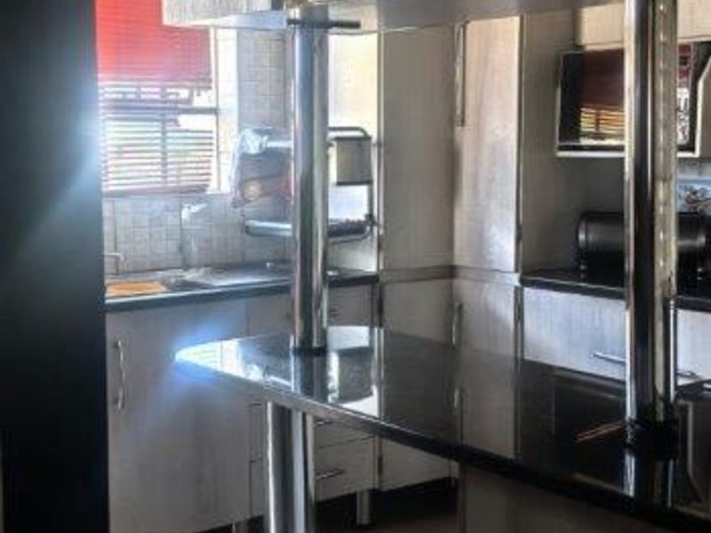 A functional kitchen featuring built-in cabinetry, granite countertops, and a breakfast bar with stainless steel support columns.
