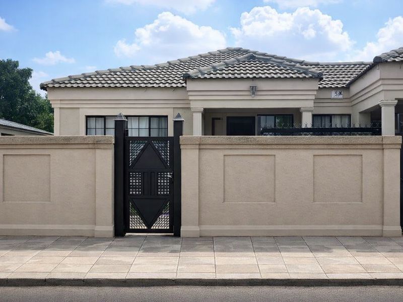 Front elevation of a single-story residence featuring a tiled roof, neutral rendered facade, and a secure metal pedestrian gate with a perimeter wall.