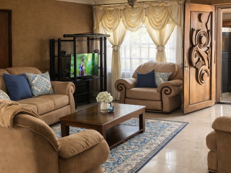 A living room featuring ornate ceiling detailing, a decorative ceiling rose, tiled flooring, and a distinctive carved wooden entrance door.