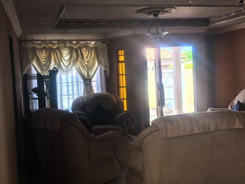 A living room featuring a recessed ceiling with decorative molding, textured wall finishes, and sliding glass doors providing access to the exterior.