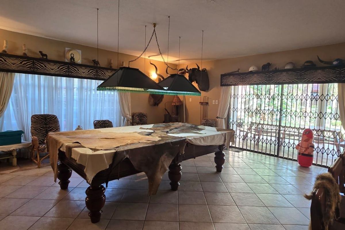Spacious living area featuring tiled flooring, large windows with decorative pelmets, and sliding security gates leading to the outdoor space.