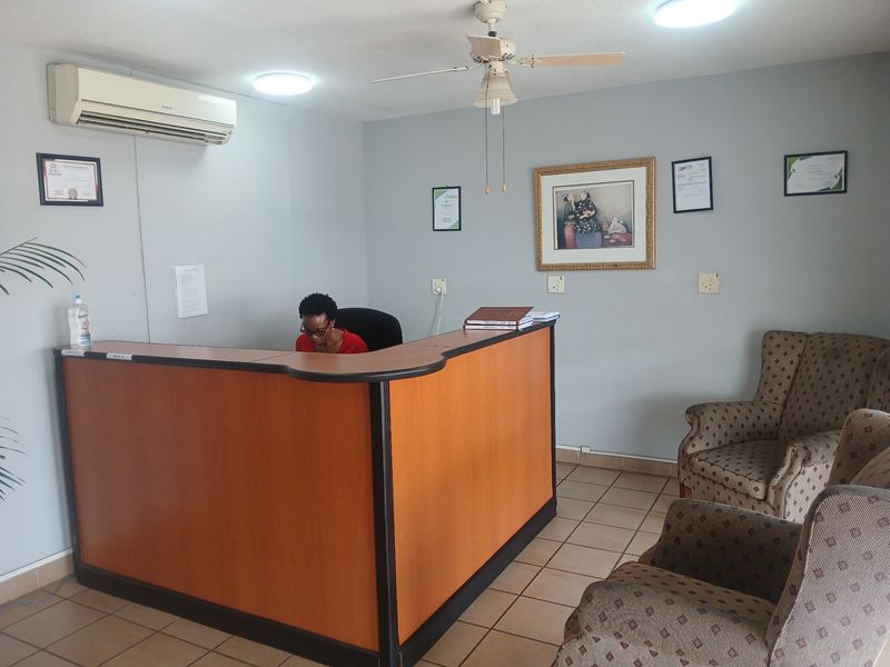 A functional commercial office reception area featuring a built-in desk, tiled flooring, and climate control, suitable for a professional business environment.