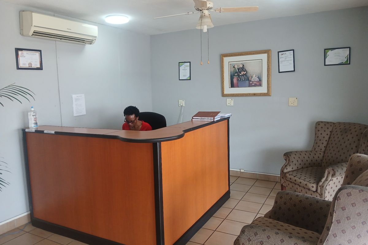 A functional commercial office reception area featuring a built-in desk, tiled flooring, and climate control, suitable for a professional business environment.