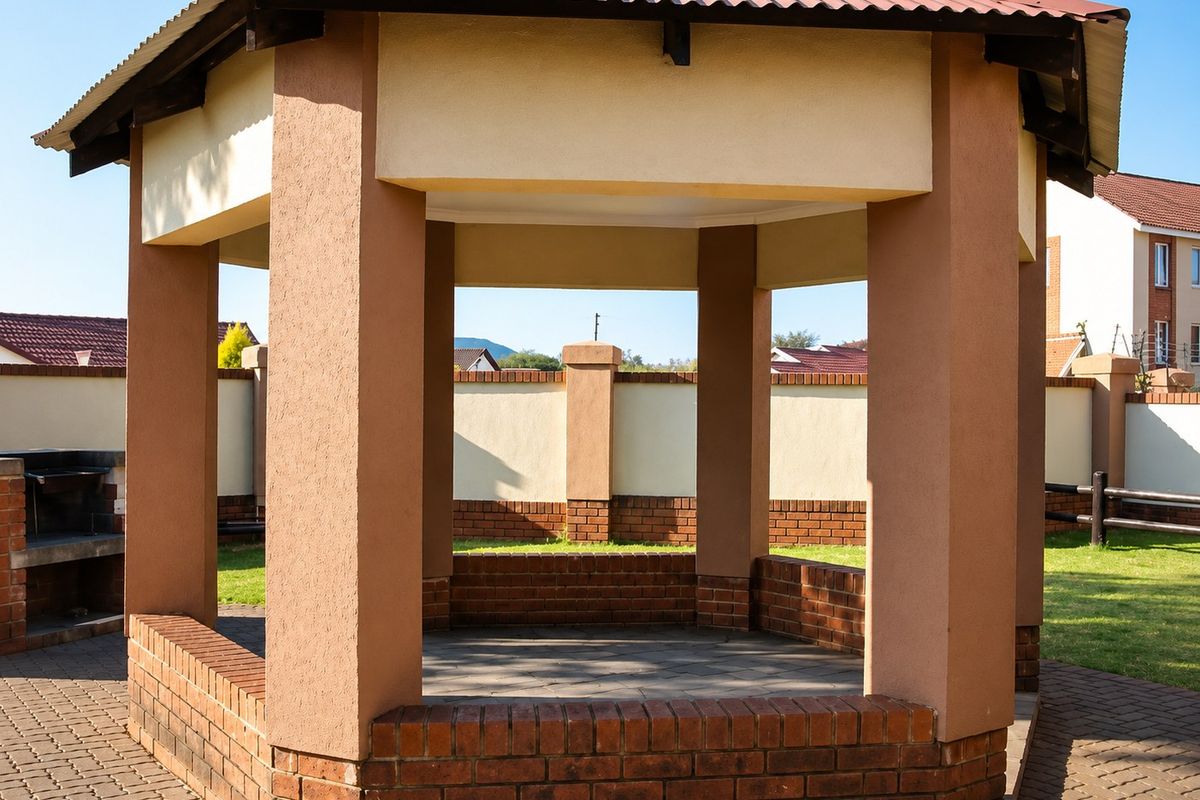 A well-maintained outdoor gazebo featuring a built-in braai area, brick paving, and a durable corrugated metal roof within a secure complex.