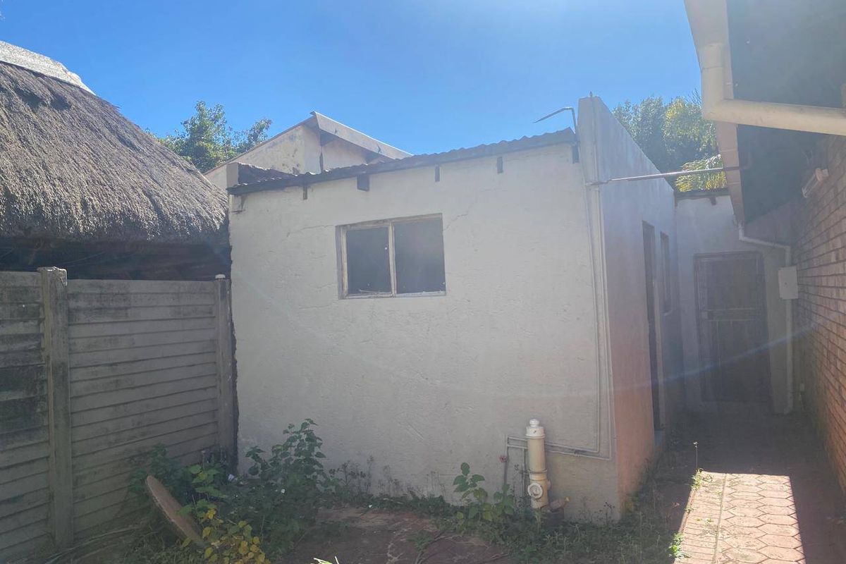Rear exterior view of the property showing a small outbuilding structure with visible wear to the roofline and exterior plaster finishes.